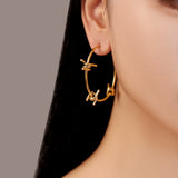 model wearing gold waterproof stainless steel barbed wire large hoop earrings