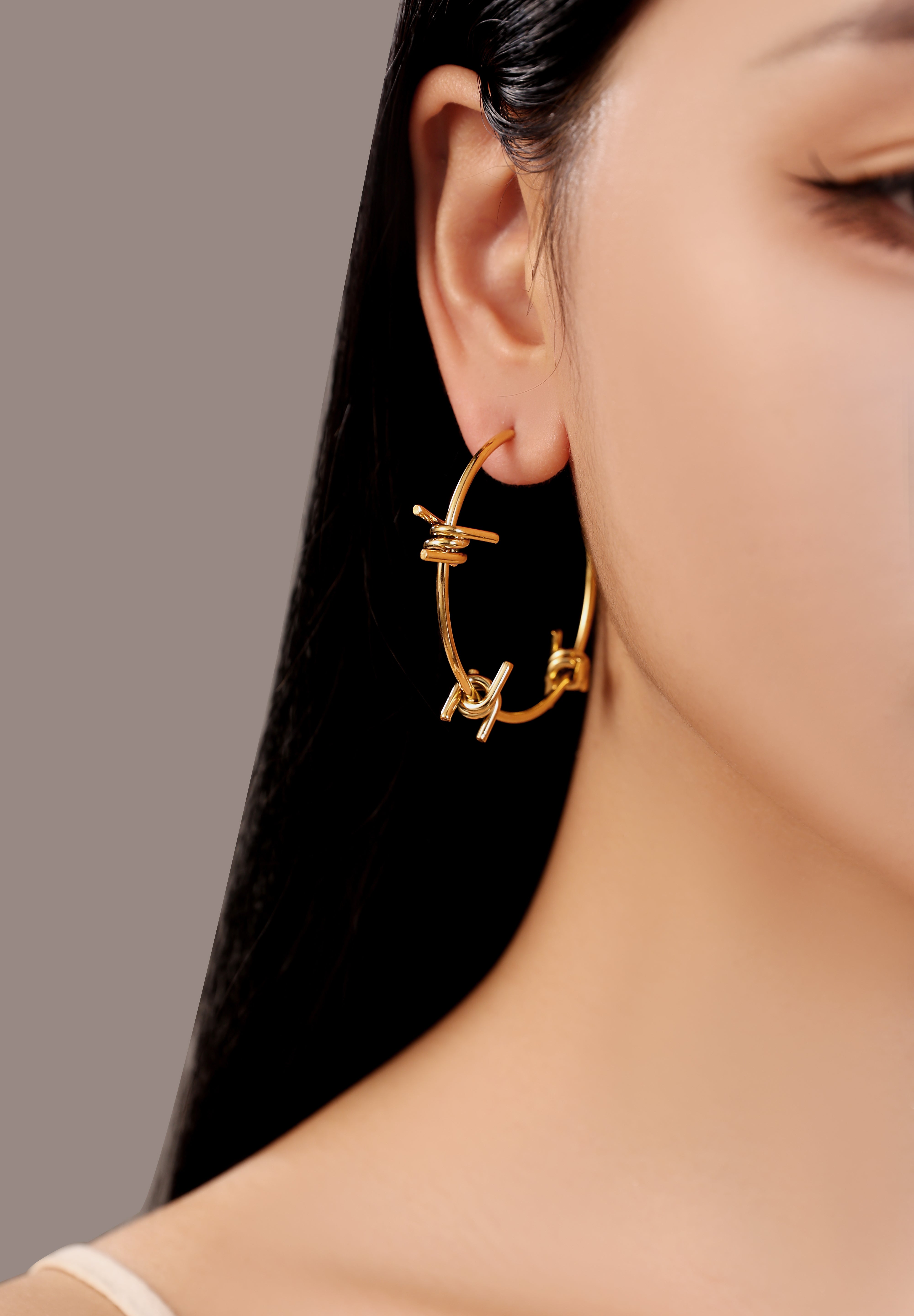 model wearing gold waterproof stainless steel barbed wire large hoop earrings