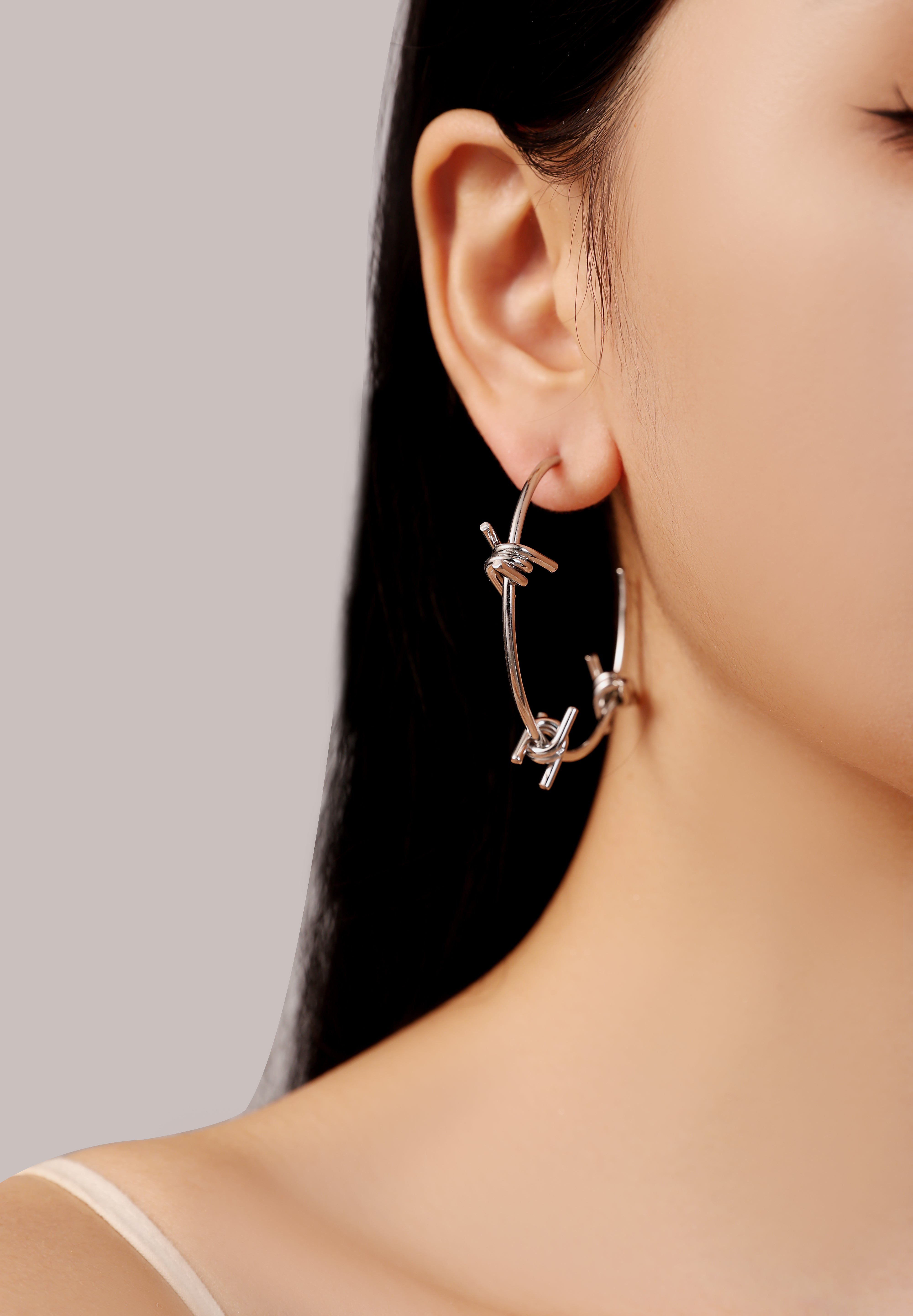 model wearing silver waterproof stainless steel barbed wire large hoop earrings
