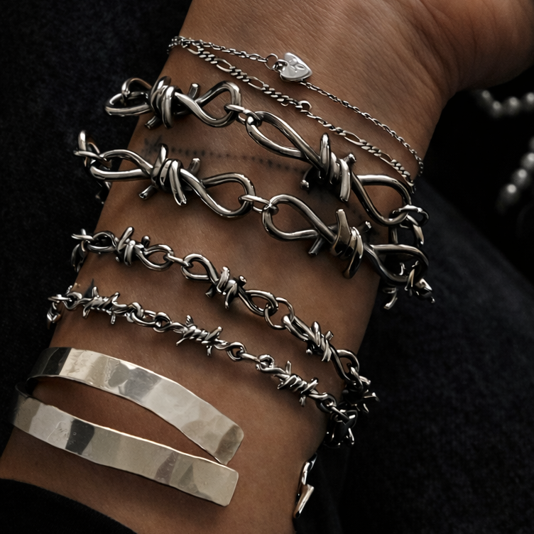 Silver bracelets on a wrist against a dark background