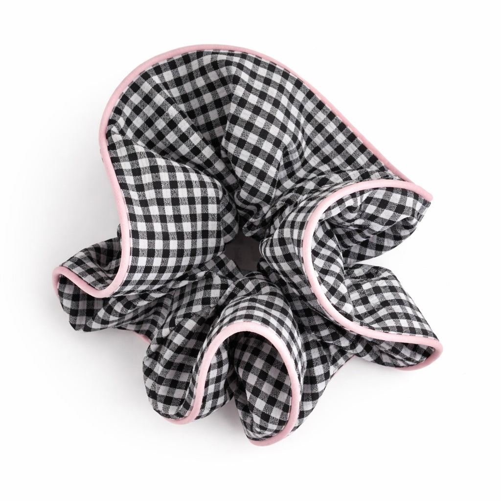 Black and white checkered scrunchie with pink trim on a white background