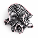 Black and white checkered scrunchie with pink trim on a white background