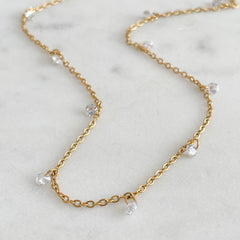 Gold chain necklace with small crystals on a marble surface
