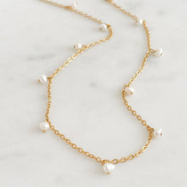Fine chain necklace with pearls on a marble background