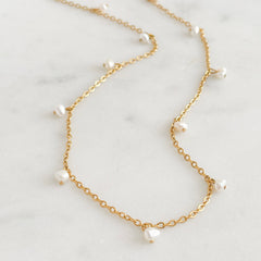 Fine chain necklace with pearls on a marble background