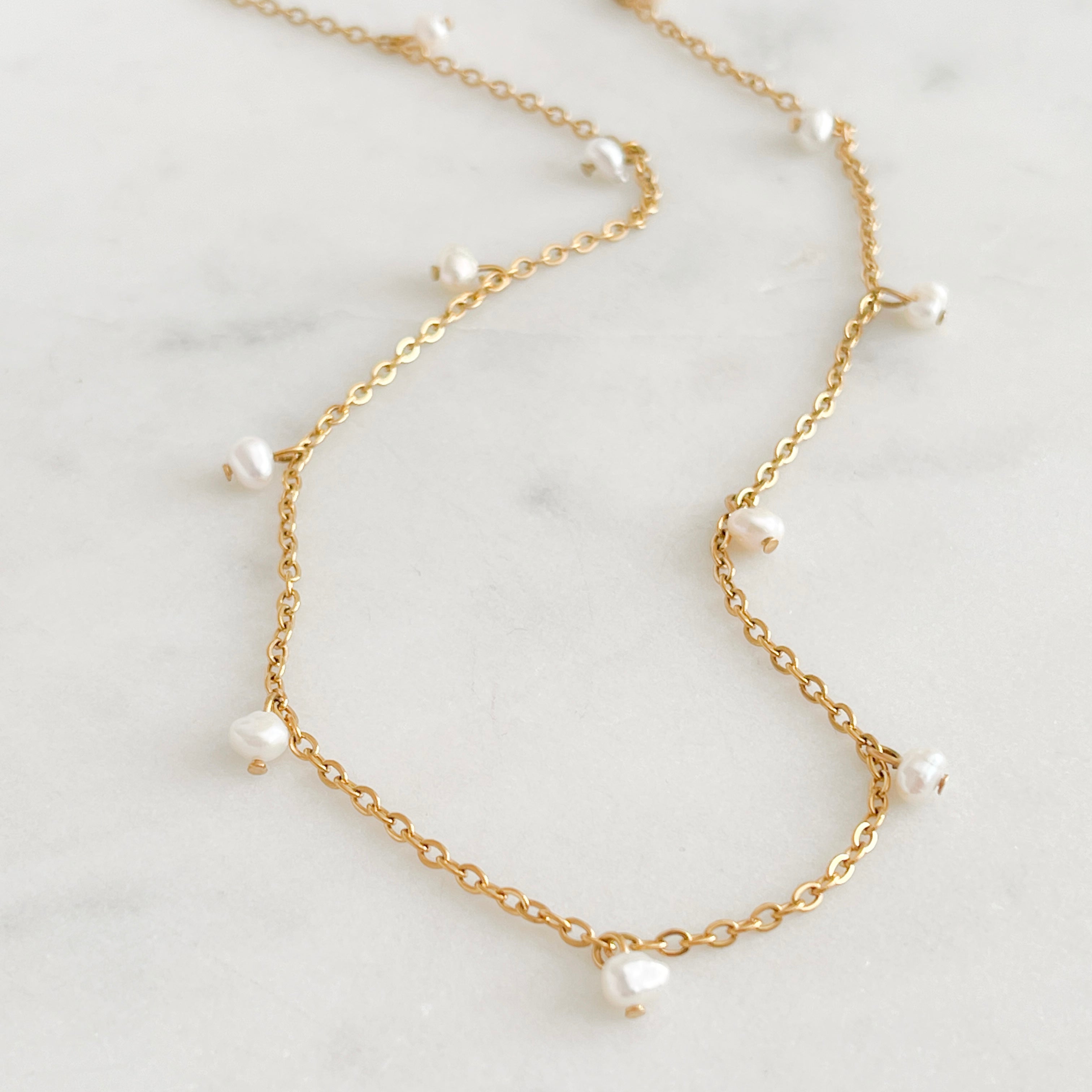 Fine chain necklace with pearls on a marble background