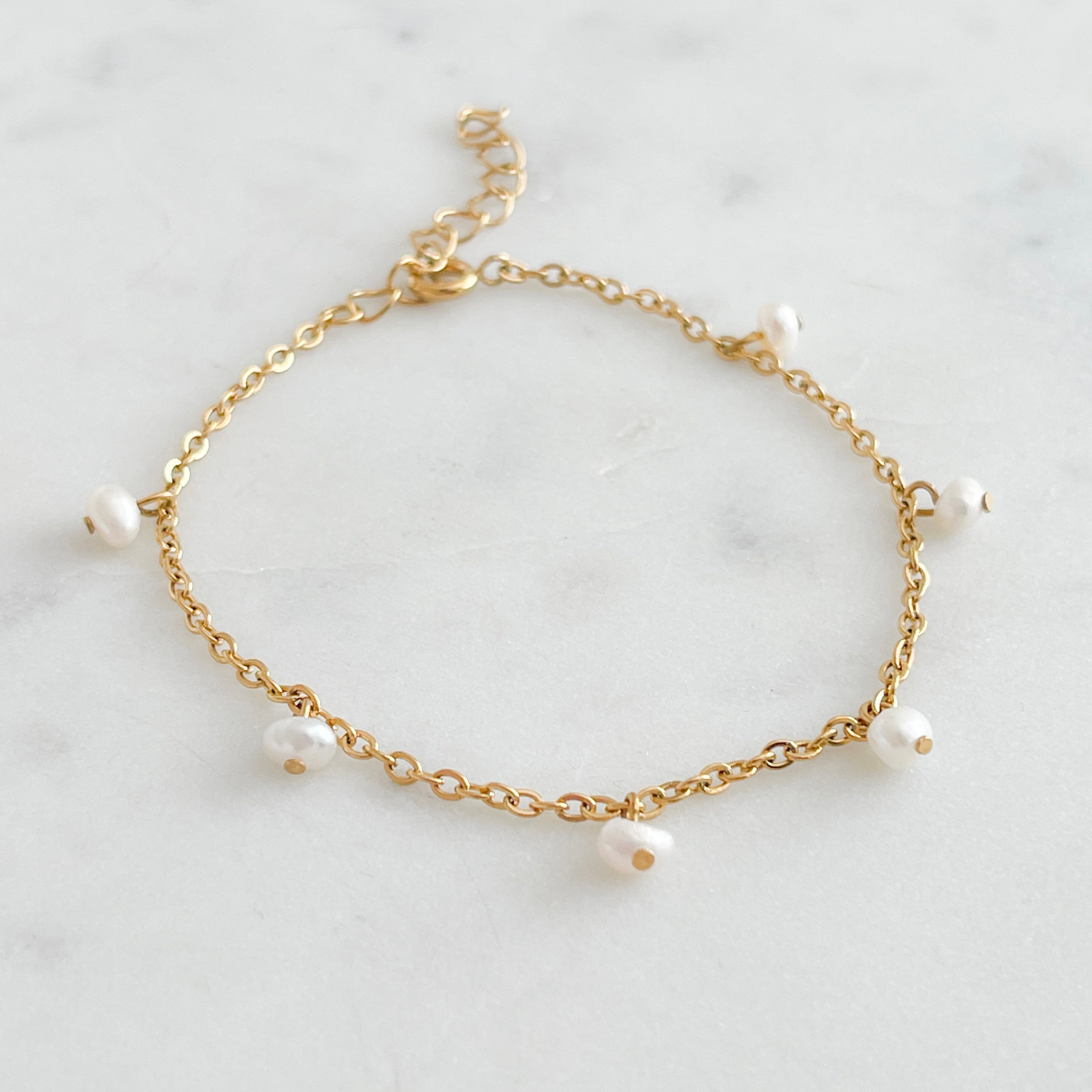 Fine Gold bracelet with small freshwater pearls on a marble background