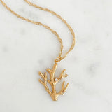 Gold coral-shaped pendant necklace on a marble background