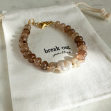 Beaded bracelet with gold clasp on a branded drawstring bag