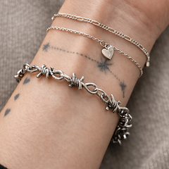 Close-up of a wrist wearing multiple silver bracelets on a neutral background