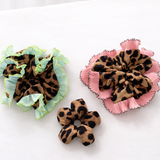 three leopard scrunchies on a white surface