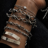 Hand wearing multiple silver bracelets on a dark background